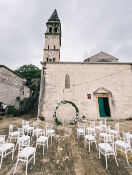 Rows of white chairs stand in front of the church of St. Nicholas in Perast. Montenegro. High quality photo