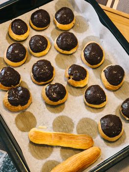 Choux cakes with craquelins lie on baking paper on a baking sheet. High quality photo