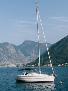 White sailing yacht is moored in the sea against the backdrop of mountains. High quality photo