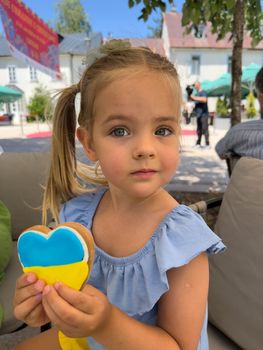 Little girl holding blue and yellow heart shaped cookies. High quality photo