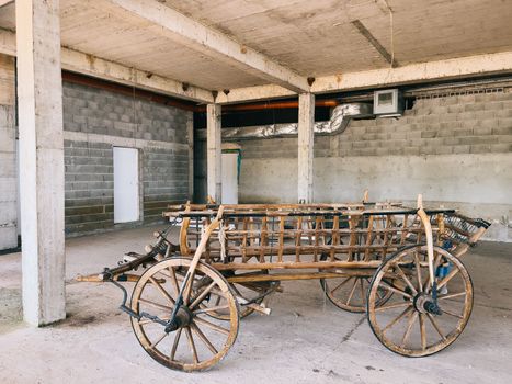 Wooden cart on wheels stands under a concrete canopy in a parking lot. High quality photo