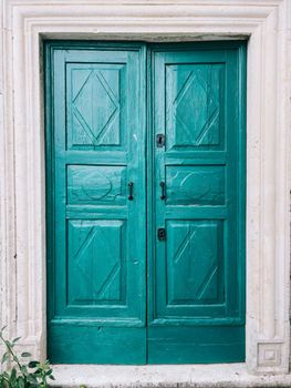 Green wooden door with white stone frame. High quality photo