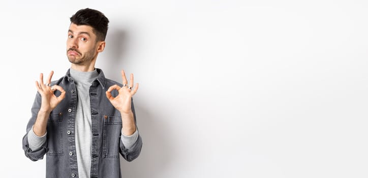 Not bad. Impressed handsome guy nod in approval, showing okay signs to make compliment, praise good work, like result, standing on white background.