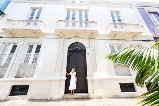 Tenerife, Canary Islands, Spain. A girl in a white dress stands against the wall of a house in Santa Cruz de Tenerife