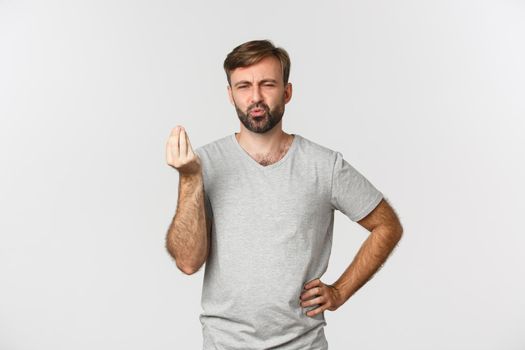 Image of handsome caucasian man showing chefs kiss sign and praising tasty food, pouting delighted, standing over white background.