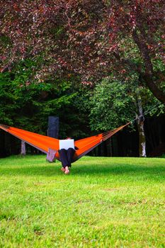 Woman working on her computer lying on hammock