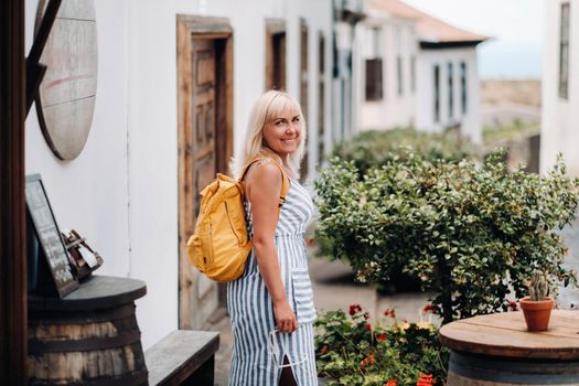 a blonde in a sundress with a backpack walks along the street of the Old town of Garachico on the island of Tenerife.Spain, Canary Islands