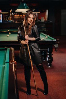 A girl with a cue in her hands is standing in a billiard club.Russian billiards.