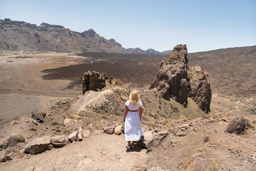 a girl in a white dress stands in the crater of the Teide volcano.Tenerife, Canary Islands.