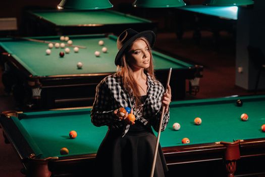 A girl in a hat in a billiard club with a cue in her hands.billiards Game.