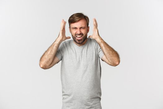 Portrait of angry bearded man, shouting and shaking hands frustrated, standing mad over white background.