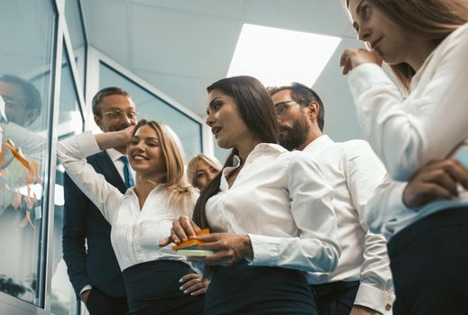 Group of business peoples glue stickers at glass wall in office. Teamwork concept. Toned image. High quality photo.