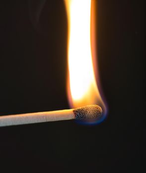 A selective focus of a match on fire on black background