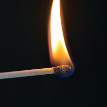 A selective focus of a match on fire on black background