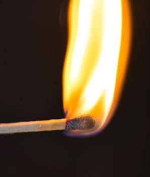 A selective focus of a match on fire on black background