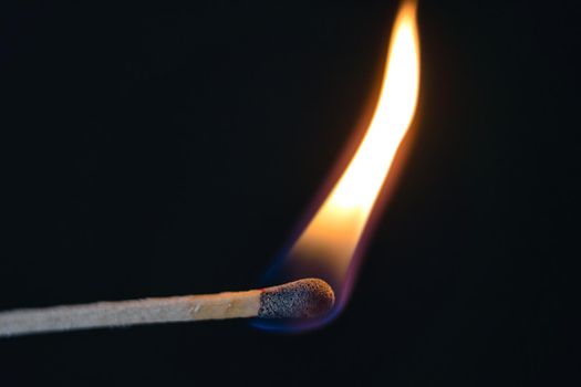 A selective focus of a match on fire on black background