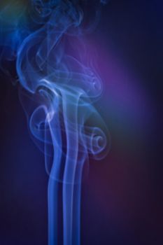 A vertical shot of smoke in colorfull backlight with a blue note