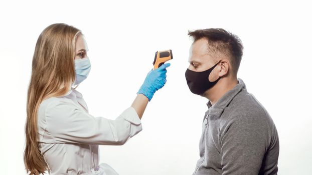 Checking patient body temperature test using a non-contact thermometer nurse wearing a medical mask and blue disposable gloves. Isolated on white background.