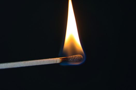 A selective focus of a match on fire on black background