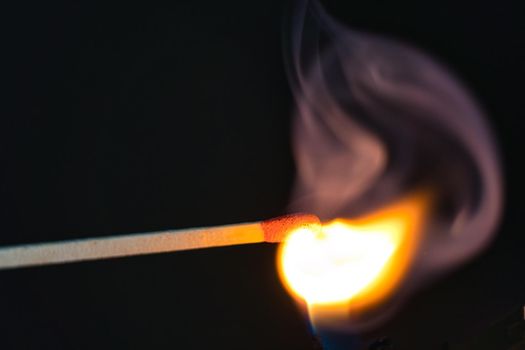 A selective focus of a match on fire on black background