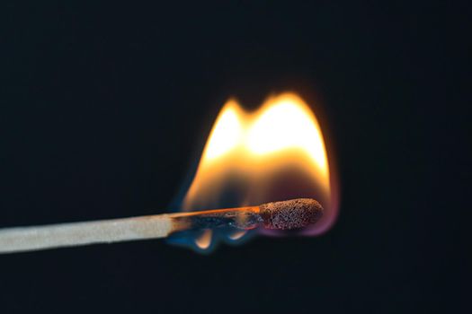 A selective focus of a match on fire on black background