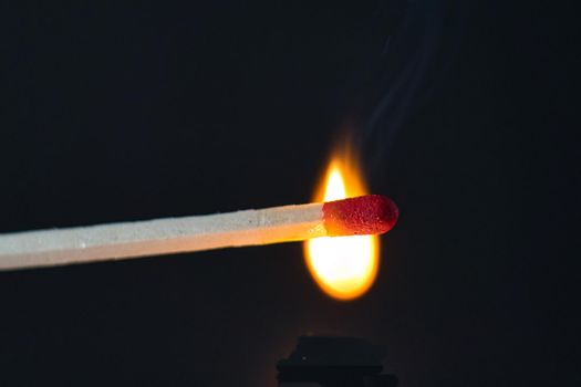 A selective focus of a match on fire on black background