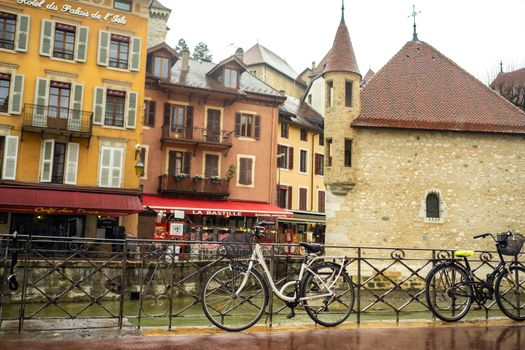 ANNECY, FRANCE-APRIL 3, 2019: The Tioux River embankment in the Old Town, surrounding a medieval palace located in the middle of the river-the Ile Palace on a rainy day.