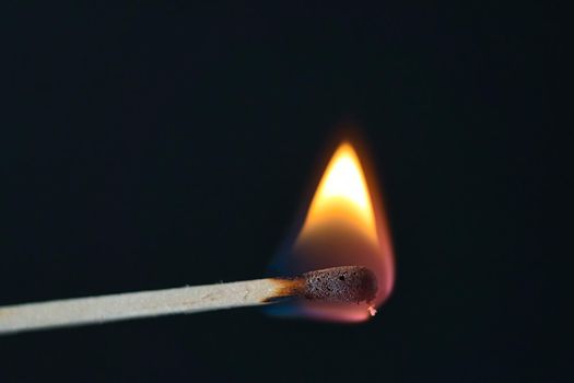 A selective focus of a match on fire on black background