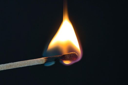 A selective focus of a match on fire on black background