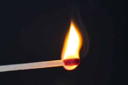 A selective focus of a match on fire on black background