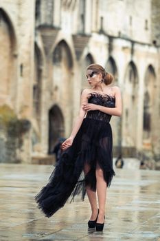 A stylish bride in a black wedding dress in the ancient French city of Avignon. A model in a black dress.