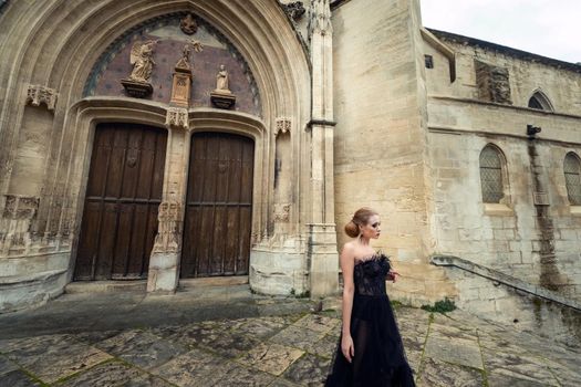 A stylish bride in a black wedding dress in the ancient French city of Avignon. A model in a black dress.