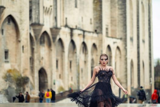 A stylish bride in a black wedding dress in the ancient French city of Avignon. A model in a black dress.