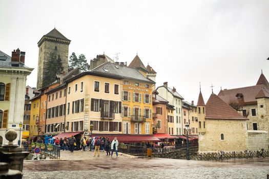 ANNECY, FRANCE-APRIL 3, 2019: The Tioux River embankment in the Old Town, surrounding a medieval palace located in the middle of the river-the Ile Palace on a rainy day.