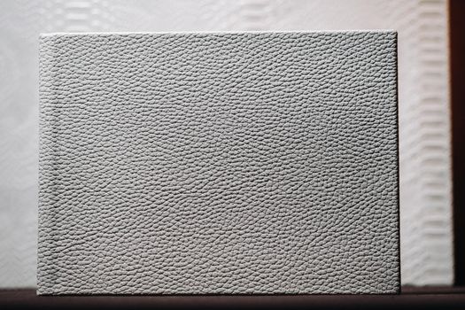 Composition of photo books in natural white leather of different sizes. The white paper on a dark background