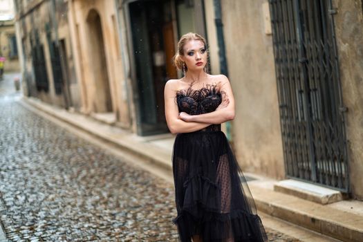 A stylish bride in a black wedding dress in the ancient French city of Avignon. A model in a black dress.