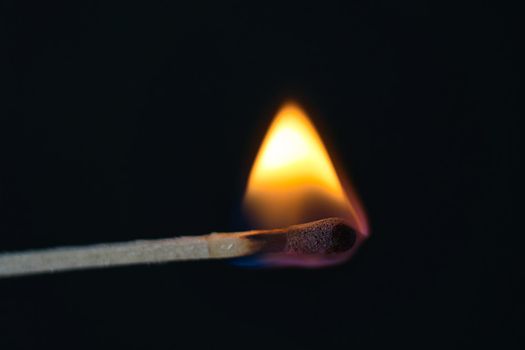 A selective focus of a match on fire on black background