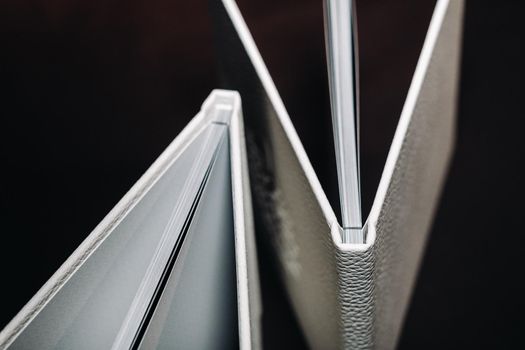 Composition of photo books in natural white leather of different sizes. The white paper on a dark background