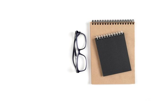 Two notepads and glasses lie on a white surface. Recycled paper notebook as a concept of ecology, recyclable, no waste. Office, business, education. Selective focus. Copy space.