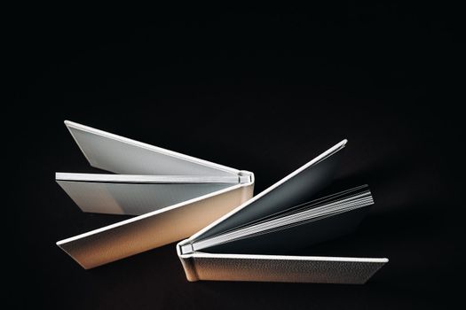 Composition of photo books in natural white leather of different sizes. The white paper on a dark background