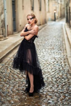 A stylish bride in a black wedding dress in the ancient French city of Avignon. A model in a black dress.