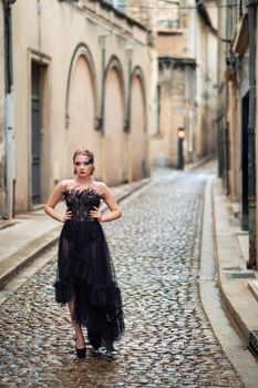 A stylish bride in a black wedding dress in the ancient French city of Avignon. A model in a black dress.