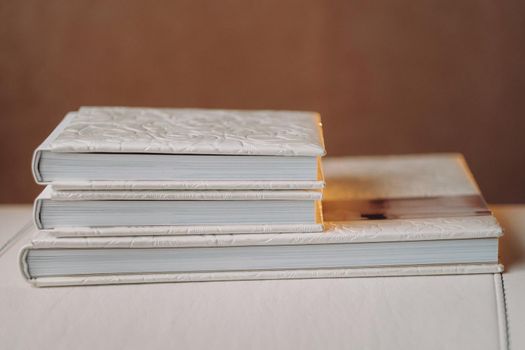 Composition of photo books in natural white leather of different sizes. Fragment of a photobook binding