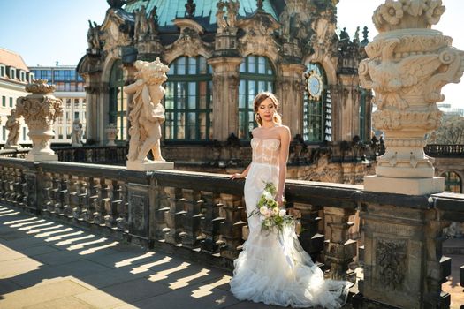 A bride in a white dress with a bouquet on a wedding walk at the famous Baroque Zwinger Palace in Dresden, Saxony, Germany.