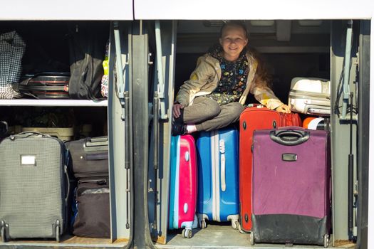 a little girl hid in the cargo compartment of a bus with suitcases.