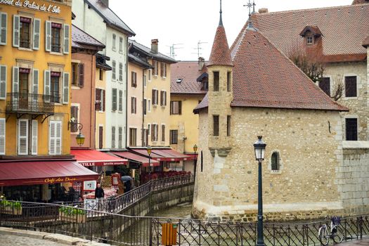 ANNECY, FRANCE-APRIL 3, 2019: The Tioux River embankment in the Old Town, surrounding a medieval palace located in the middle of the river-the Ile Palace on a rainy day.
