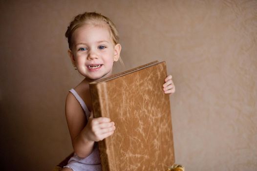 a little girl is holding a photo book in natural brown leather