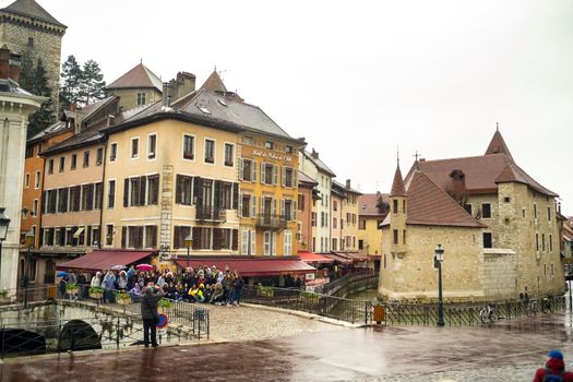 ANNECY, FRANCE-APRIL 3, 2019: The Tioux River embankment in the Old Town, surrounding a medieval palace located in the middle of the river-the Ile Palace on a rainy day.