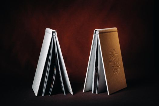 Composition of photo books in natural white leather of different sizes. The white paper on a dark background