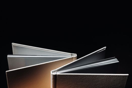 Composition of photo books in natural white leather of different sizes. The white paper on a dark background